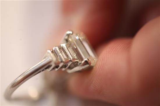 A 1930s/1940s Art Deco platinum and single stone emerald cut diamond ring, with graduated baguette cut diamond set shoulders,